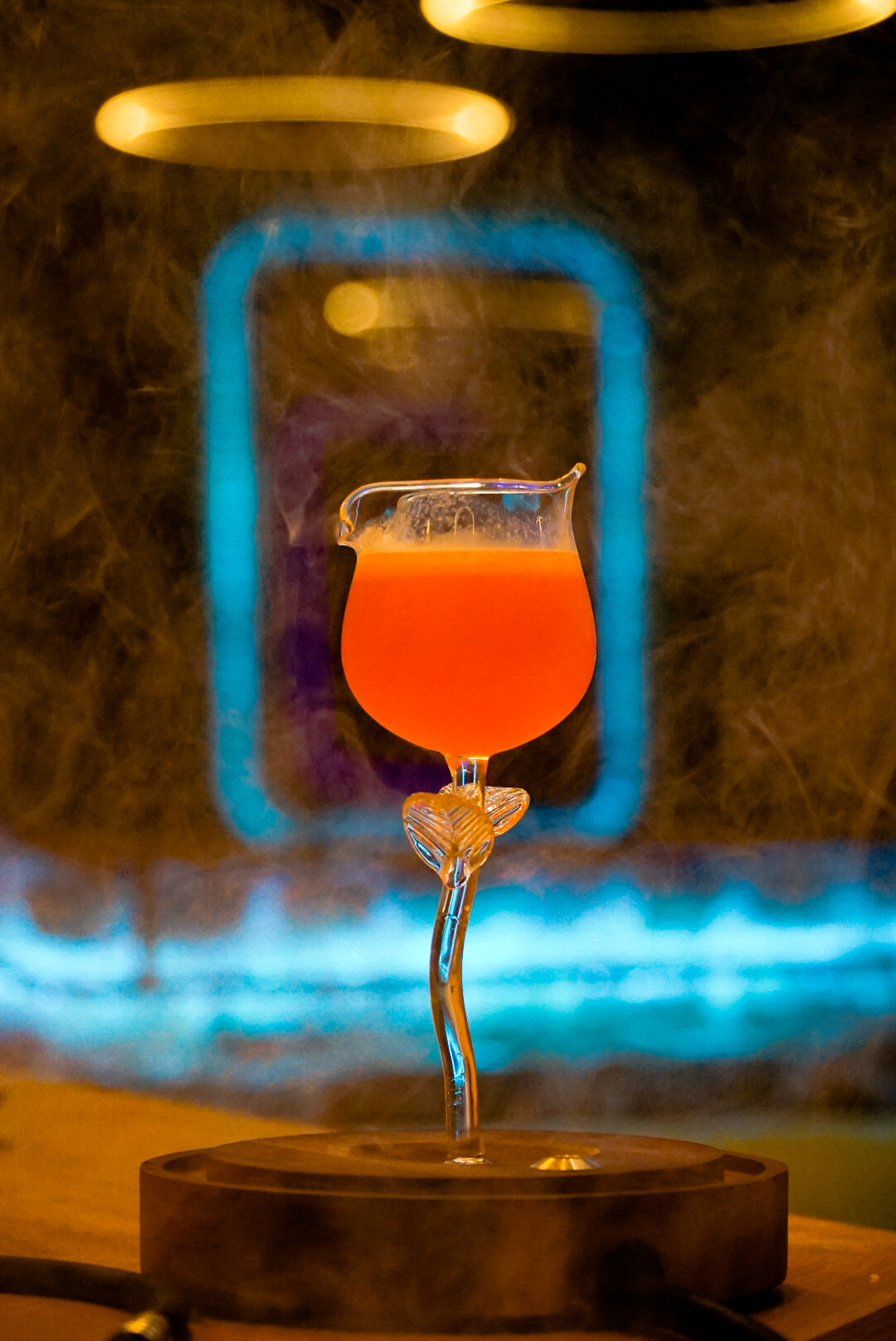 The signature rose-cup mocktail at Kakes, lit blue and rolling with smoke