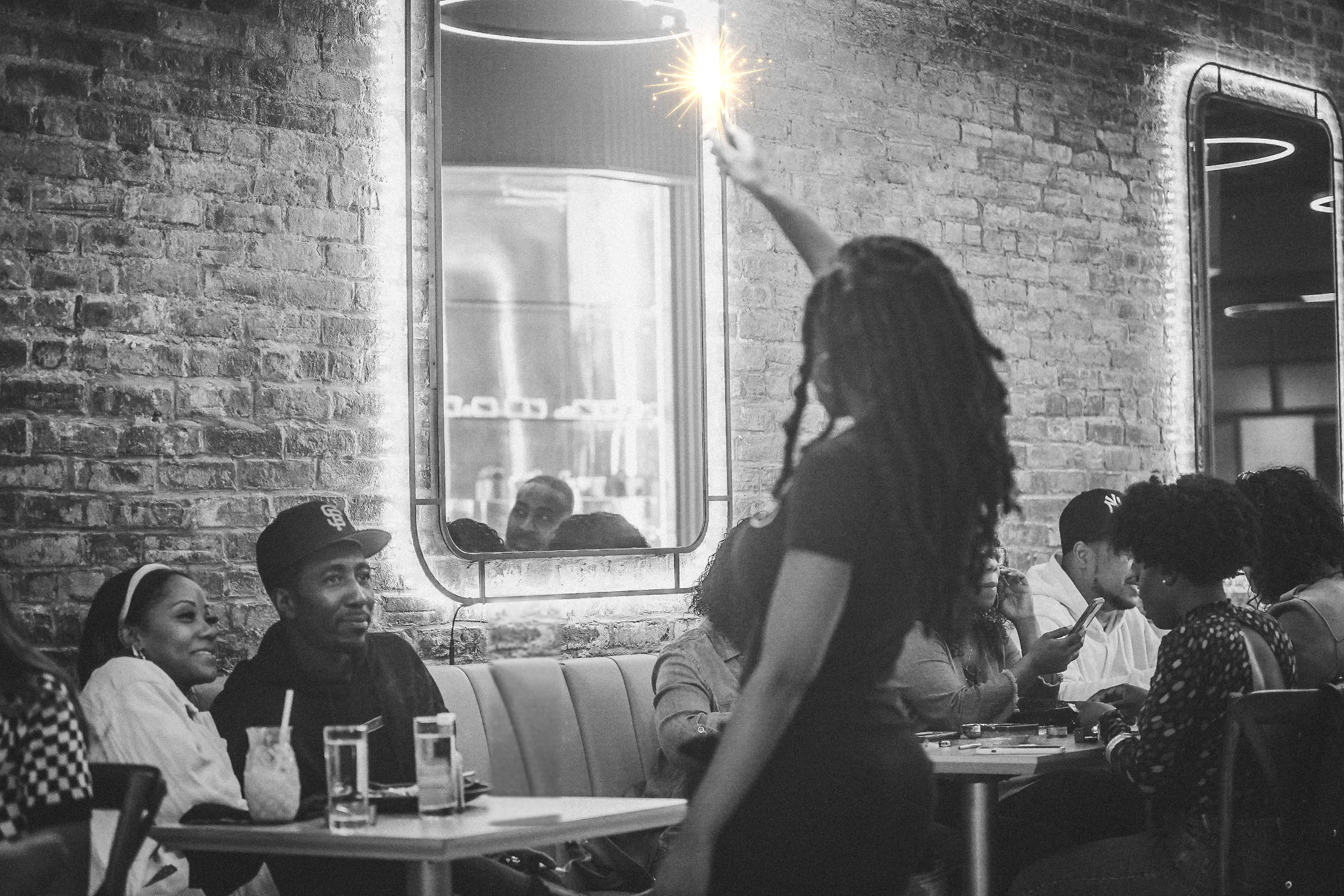 A bottle-service server raising a lit sparkler over a full dining room at Kakes