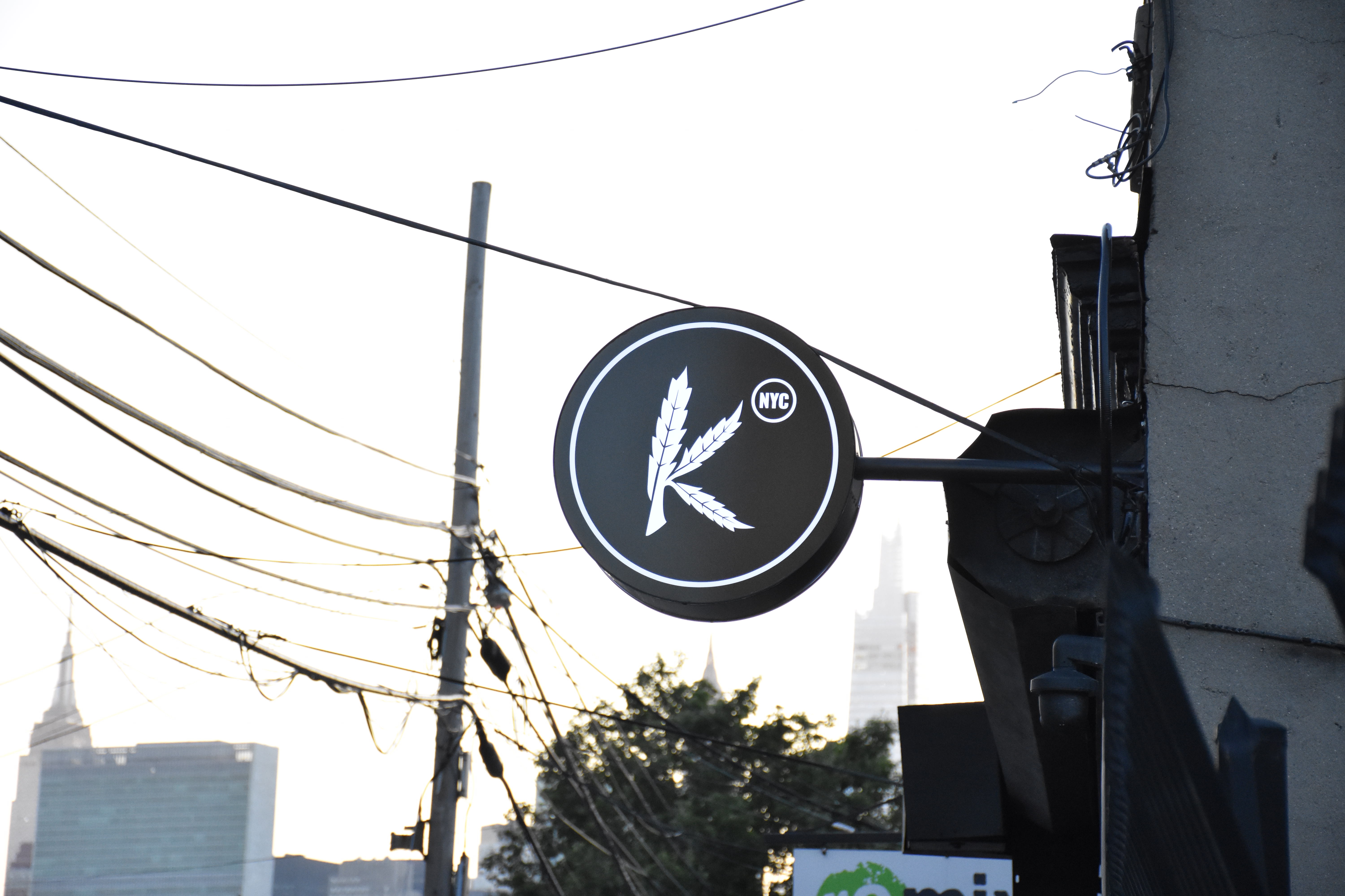 The Kakes circular K sign on 44th Drive, Long Island City, with the Manhattan skyline behind